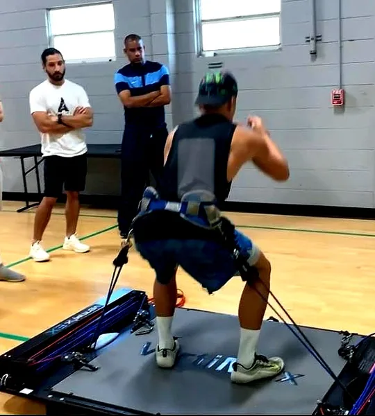 Athlete performing a resisted sprint drill on a Vertimax training platform